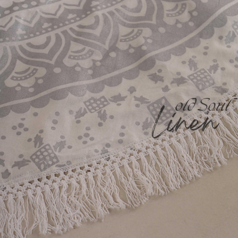 May include: A white round tapestry with a gray mandala design and white fringe. The tapestry has the text "Old Soul Linen" printed on it.