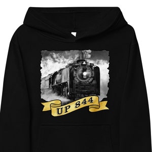 Puede incluir: Imagen en blanco y negro de una locomotora de vapor vintage con el texto "UP 844" en una cinta dorada.