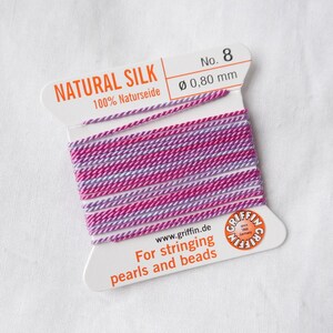 Peut inclure: Une bobine de fil de soie naturelle rose et violet pour enfiler des perles et des perles. La bobine est étiquetée "NATURAL SILK 100% Naturseide No. 8 Ø 0,80 mm" et "www.griffin.de For stringing pearls and beads".