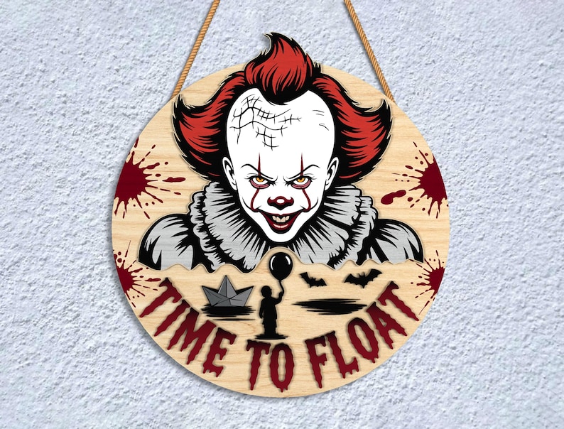 May include: Round wooden sign featuring a menacing clown with red hair and makeup, surrounded by blood splatters. The sign reads "TIME TO FLOAT" in red lettering, with a paper boat, a child holding a balloon, and bats. A rope is attached for hanging.