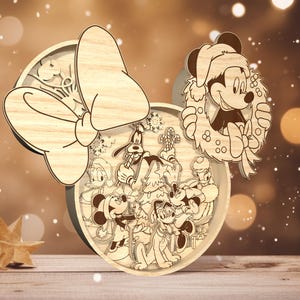 May include: A wooden Christmas ornament featuring a festive wreath with Mickey Mouse, Minnie Mouse, Pluto, Donald Duck, and Goofy. The ornament is decorated with a large bow and snowflakes.