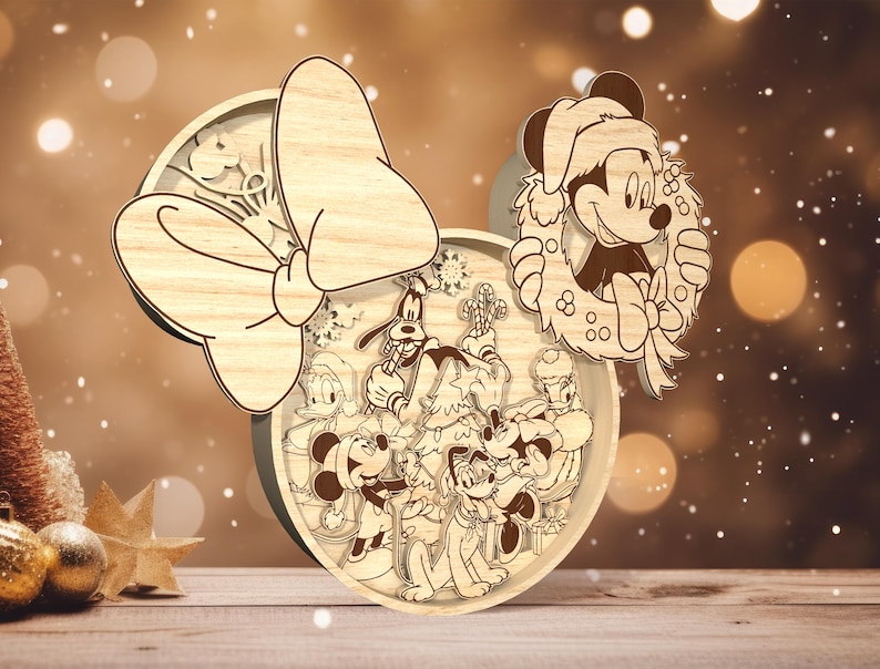 May include: A wooden Christmas ornament featuring a festive wreath with Mickey Mouse, Minnie Mouse, Pluto, Donald Duck, and Goofy. The ornament is decorated with a large bow and snowflakes.