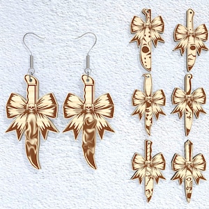 May include: Wooden earrings featuring a knife design with a bow and skull. The earrings have a light brown color with darker brown accents. Additional knife-shaped pendants with bow and skull designs are also visible.