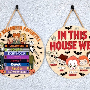 May include: Two round wooden Halloween signs. One says "OUR HALLOWEEN FAVORITES" with images of characters and book titles. The other says "IN THIS HOUSE WE..." with character faces and phrases. Both have rope hangers.