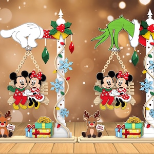 Könnte beinhalten: Zwei Weihnachtsdekorationen aus Holz. Eine zeigt Mickey und Minnie Mouse auf einer Schaukel, mit einem Rentier, Geschenken und dem Text "Happy Holidays". Eine hat einen weißen Handschuh, die andere eine grüne Hand. Festliche Weihnachtsdekoration.