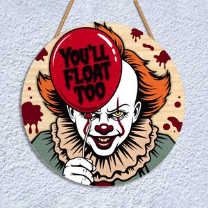 May include: Round wooden sign featuring a menacing clown with orange hair and a red nose, holding a red balloon with the text "YOU'LL FLOAT TOO." The sign has a rope for hanging and is decorated with blood splatters.