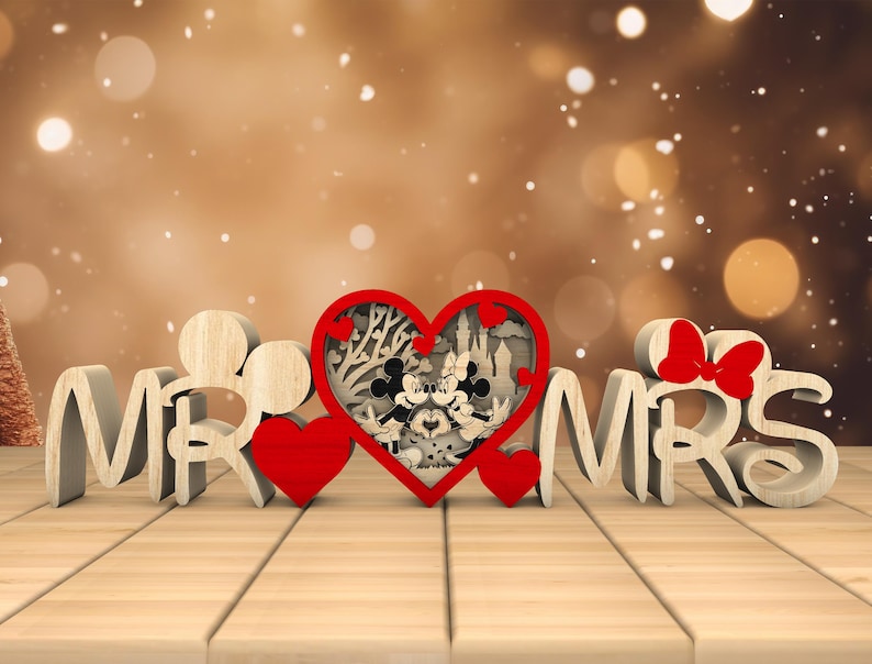 May include: Wooden "Mr." and "Mrs." sign with a red heart in the middle. The heart has a cutout design of Mickey and Minnie Mouse in front of a castle.