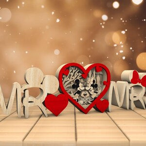 May include: Wooden "Mr." and "Mrs." sign with a red heart in the centre. The heart features a cutout design of Mickey and Minnie Mouse.