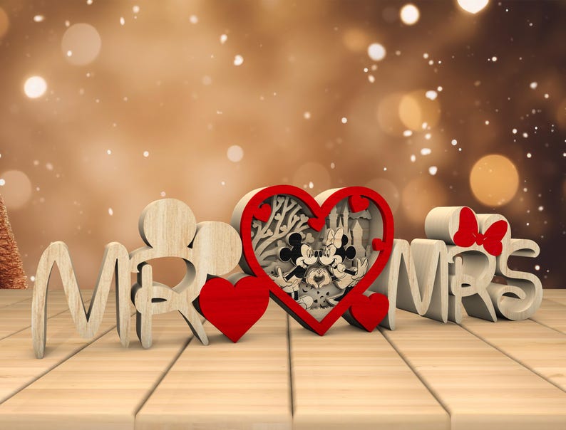 May include: Wooden "Mr." and "Mrs." sign with a red heart in the centre. The heart features a cutout design of Mickey and Minnie Mouse.