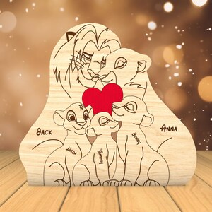 K&ouml;nnte beinhalten: Holzausschnitt einer L&ouml;wenfamilie mit einem roten Herzen in der Mitte. Die L&ouml;wenfamilie besteht aus einem Vaterl&ouml;wen, einer Mutterl&ouml;win und zwei Jungen. Die Namen Jack, Linda, Tommy, Benny und Anna sind auf den Ausschnitt geschrieben.