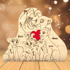 K&ouml;nnte beinhalten: Ein Holzausschnitt einer L&ouml;wenfamilie mit den Namen Jack, Anna, David, Remus, Linda, Tommy und Benny. Die L&ouml;wenfamilie h&auml;lt ein rotes Herz.