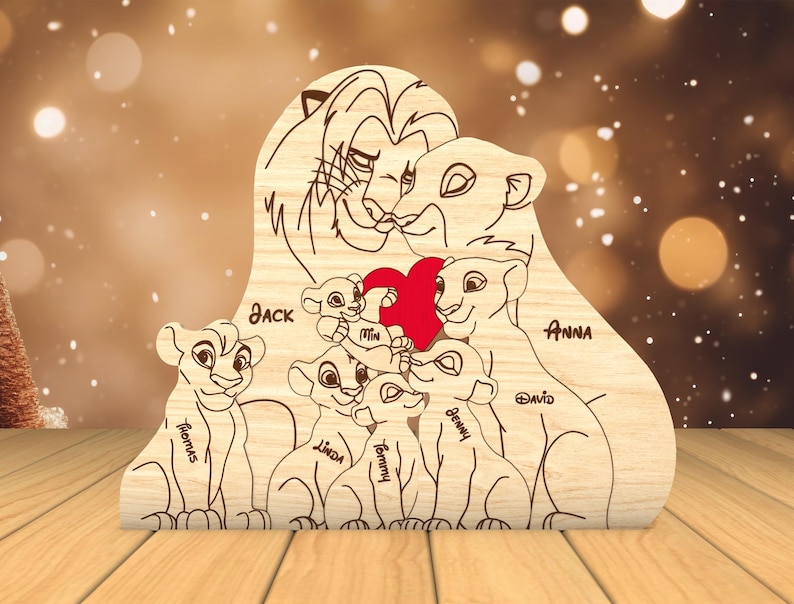 K&ouml;nnte beinhalten: Ein Holzausschnitt einer L&ouml;wenfamilie mit den Namen Jack, Anna, David, Remus, Linda, Tommy und Benny. Die L&ouml;wenfamilie h&auml;lt ein rotes Herz.