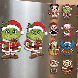 Op de afbeelding: Een verzameling decoratieve koelkastmagneten met diverse stripfiguren in kerstkleding, waaronder twee grote Grinch-figuren, Mickey en Minnie Mouse, Donald en Daisy Duck, Pluto, Stitch, Knorretje, Teigetje en eekhoorns.