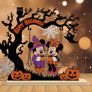 May include: A Halloween-themed wooden decoration featuring Mickey and Minnie Mouse on a swing, holding mugs. The design includes a tree with the words "Happy Halloween", pumpkins, bats, ghosts, and spiderwebs. The color scheme is orange, black, and white.