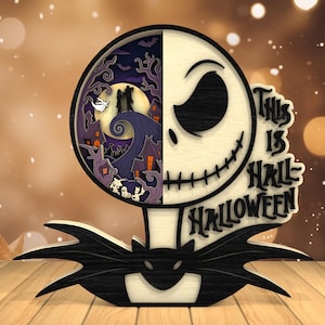 May include: A layered wooden Halloween decoration featuring Jack Skellington's face on the right and a spooky scene on the left. The text "This is Halloween" is displayed. The decoration is black, white, and purple.