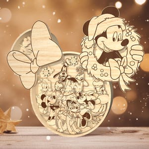 May include: A wooden Christmas ornament featuring Mickey Mouse and Minnie Mouse with other Disney characters. The ornament is shaped like Minnie Mouse's head with a large bow and a wreath around Mickey Mouse's head.