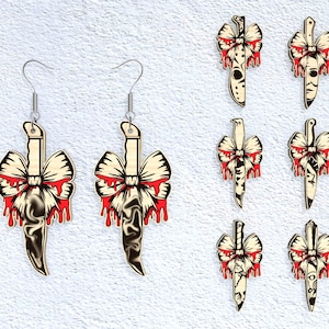 May include: Wooden knife earrings with a cream-colored bow and red dripping blood design. The earrings have silver-colored hooks. Additional knife-shaped pendants with similar designs are also shown.