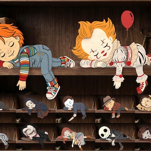 Peut inclure: Une collection de figurines en bois à poser sur une étagère représentant divers personnages de films d'horreur en position de sommeil. Les personnages incluent Chucky, Pennywise avec un ballon rouge, Ghostface, une nonne, Michael Myers, Freddy Krueger, Jason, Beetlejuice et Jack Skellington.