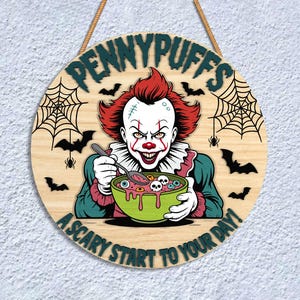May include: Round wooden sign with the text "PENNYPUFFS" and "A SCARY START TO YOUR DAY!". The sign features a clown holding a bowl of food with eyeballs and skulls. Bats and spiderwebs decorate the sign.