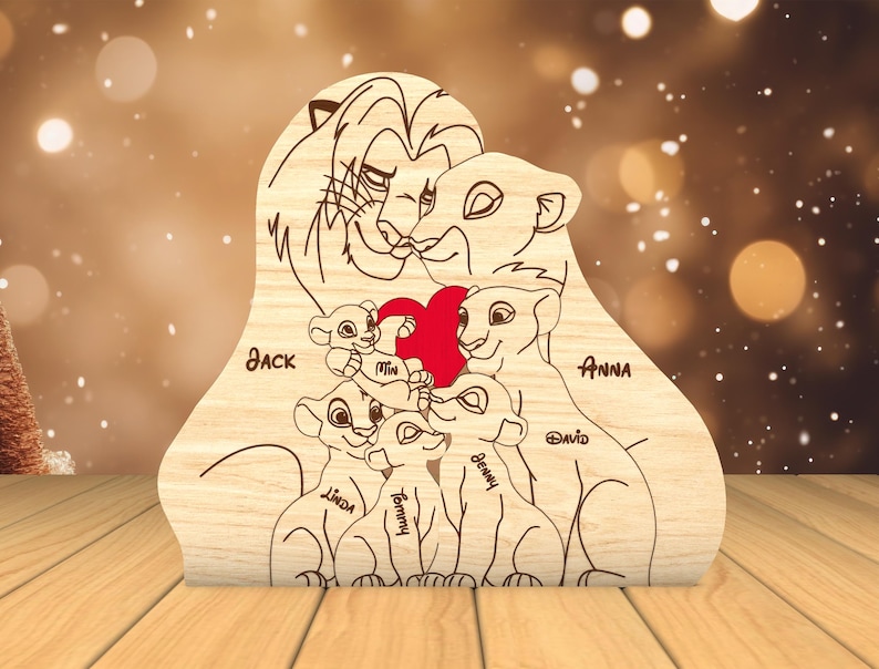 K&ouml;nnte beinhalten: Ein Holzausschnitt einer L&ouml;wenfamilie mit einem roten Herzen in der Mitte. Die Eltern sind mit "Jack" und "Anna" beschriftet und die Kinder mit "Mia", "Linda", "Tommy", "Benny" und "David".