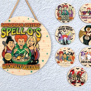 Puede incluir: Un letrero redondo de madera con el texto "Sanderson Sisters Spell-O's Witchfully Delicious!" y una imagen de dibujos animados de tres brujas. También hay varios posavasos redondos con diseños de Halloween.