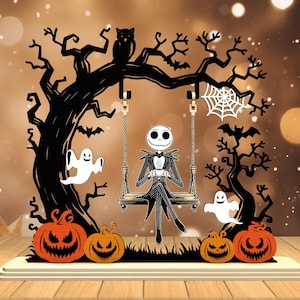 May include: A Halloween-themed decoration featuring a silhouette of a tree with a swing. Jack Skellington is seated on the swing, holding a cup. The scene includes pumpkins, ghosts, bats, and an owl. The color scheme is black, orange, and white.