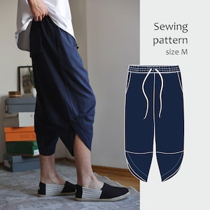 May include: Navy blue cropped pants with a unique asymmetrical design. The pants have a drawstring waist and pockets. A sewing pattern illustration is shown with the text "Sewing pattern size M". The person is wearing black and white striped espadrilles.