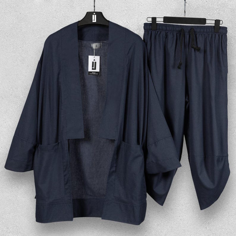 May include: A navy blue linen kimono jacket and matching drawstring trousers set. The jacket features large front pockets and a relaxed fit. The trousers have a loose, comfortable design. The set is displayed on a hanger.