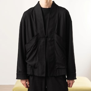 May include: A black long-sleeved jacket featuring a traditional kimono-style collar, a single central toggle closure, and two large, structured front pockets. The garment has a relaxed fit with cuffed sleeves and a solid, matte black finish.