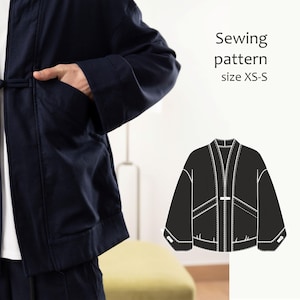 Op de afbeelding: Een donker marineblauw jasje met lange mouwen en een sluiting met een knevel, getoond naast een witte lijntekening van het kledingstuk met het label Sewing pattern size XS-S, met constructiedetails en de plaatsing van de zakken.