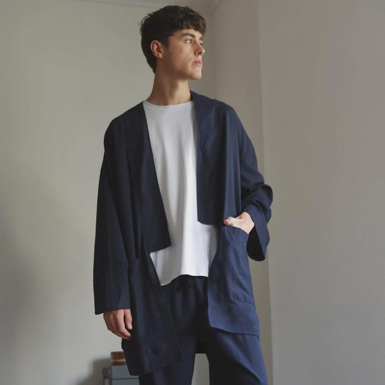 May include: A navy blue jacket with large pockets and a white t-shirt. The jacket has a relaxed fit and is open at the front. The outfit is a modern take on casual wear.