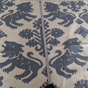 May include: White fabric with a repeating pattern of blue stylized lions and floral designs. The fabric has the text "Ragazzi - A Hand Printed Fabric Exclusively for..." printed on the side.