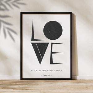 Könnte beinhalten: Schwarz-weißer geometrischer Druck des Wortes "LOVE" mit dem Bibelvers "Wir lieben, weil er uns zuerst geliebt hat. - 1 Johannes 4:19 -" darunter.