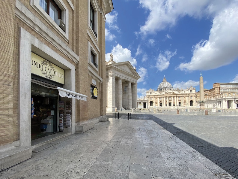 Puede incluir: Una vista de la Plaza de San Pedro en la Ciudad del Vaticano, Roma, Italia. La plaza est&aacute; vac&iacute;a, con solo unas pocas personas caminando. En el fondo, la Bas&iacute;lica de San Pedro es visible, con su ic&oacute;nica c&uacute;pula y fachada. La plaza est&aacute; rodeada por una columnata de columnas, que crean una sensaci&oacute;n de grandeza y escala.