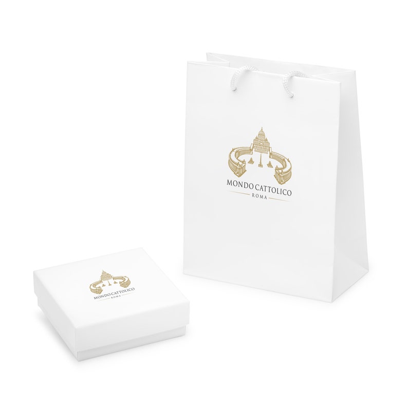 Puede incluir: Caja de regalo y bolsa de compras blancas con un logotipo dorado que presenta un dibujo de la Bas&iacute;lica de San Pedro en Roma y el texto "MONDO CATTOLICO ROMA".