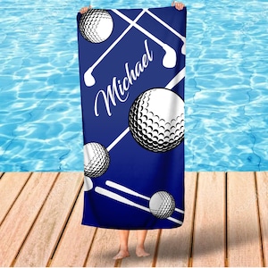 May include: A blue beach towel with white golf balls and clubs. The name "Michael" is written in white cursive on the towel.