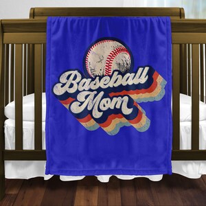 May include: A blue fleece blanket with a retro-style baseball graphic and the text "Baseball Mom" in a colorful, wavy font.