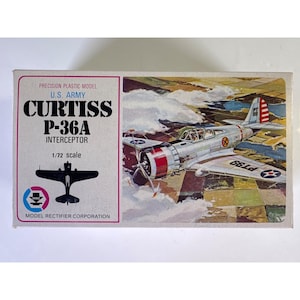 May include: A rectangular model kit box for a U.S. Army Curtiss P-36A Interceptor. The box features a 1/72 scale illustration of a silver aircraft in flight over a landscape, with the text Precision Plastic Model, Curtiss P-36A, and Model Rectifier Corporation.