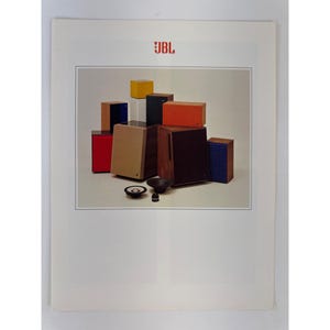 May include: A collection of JBL speakers in various sizes and colors, including red, yellow, orange, blue, and wood-grain finishes. The arrangement features several box-shaped speakers, two circular speaker drivers, and one small cylindrical component.