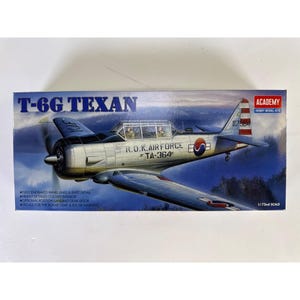 May include: A 1/72nd scale Academy hobby model kit box for a T-6G Texan aircraft. The box features a silver airplane with R.O.K. AIR FORCE markings, a detailed cockpit, and red, white, and blue tail stripes against a dark blue sky background.