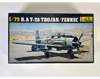 May include: A rectangular model kit box for a 1/72 scale N.A. T-28 Trojan/Fennec aircraft. The box features a detailed illustration of a silver military plane on a runway with mountains in the background and the Heller brand logo in the corner.