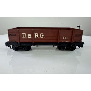 May include: A brown toy train car with the text "D. & R.G." and the number "401" printed on the side. The train car has black wheels and a small handle on top. The toy train car is made of wood.