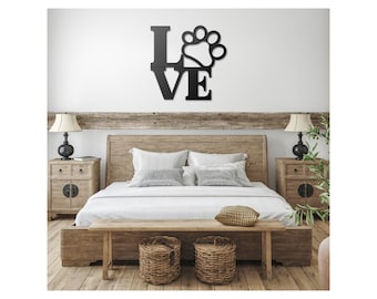 May include: Black metal wall art with the word "LOVE" and a paw print in the center. The art is hanging above a wooden bed frame with white bedding and a wooden bench.