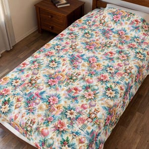 May include: A bedspread featuring a repeating holiday pattern on a cream background. The design includes nutcracker figures, pink poinsettia flowers, green pine branches, gold and pink ornaments, and wrapped gift boxes with gold ribbons.