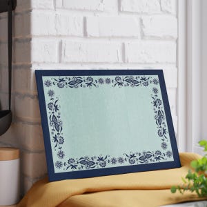 May include: A rectangular glass cutting board featuring a light mint green center panel framed by a dark navy blue border. The board is decorated with a dark navy blue floral lace pattern that runs along all four sides of the mint green surface.