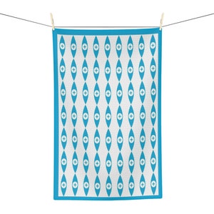 May include: A blue kitchen towel with a white eye and plus sign pattern. The towel has a blue border and is hanging on a clothesline.