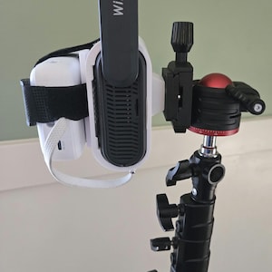May include: A white projector with a black strap and a black WiFi 6 antenna attached to a black tripod with a red ball head.