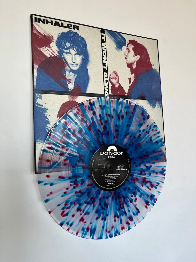 Peut inclure: Un disque vinyle avec un design de projection bleu et rouge. Le disque est intitul&eacute; "It Won't Always Be Like This" par Inhaler. Le label du disque est Polydor.