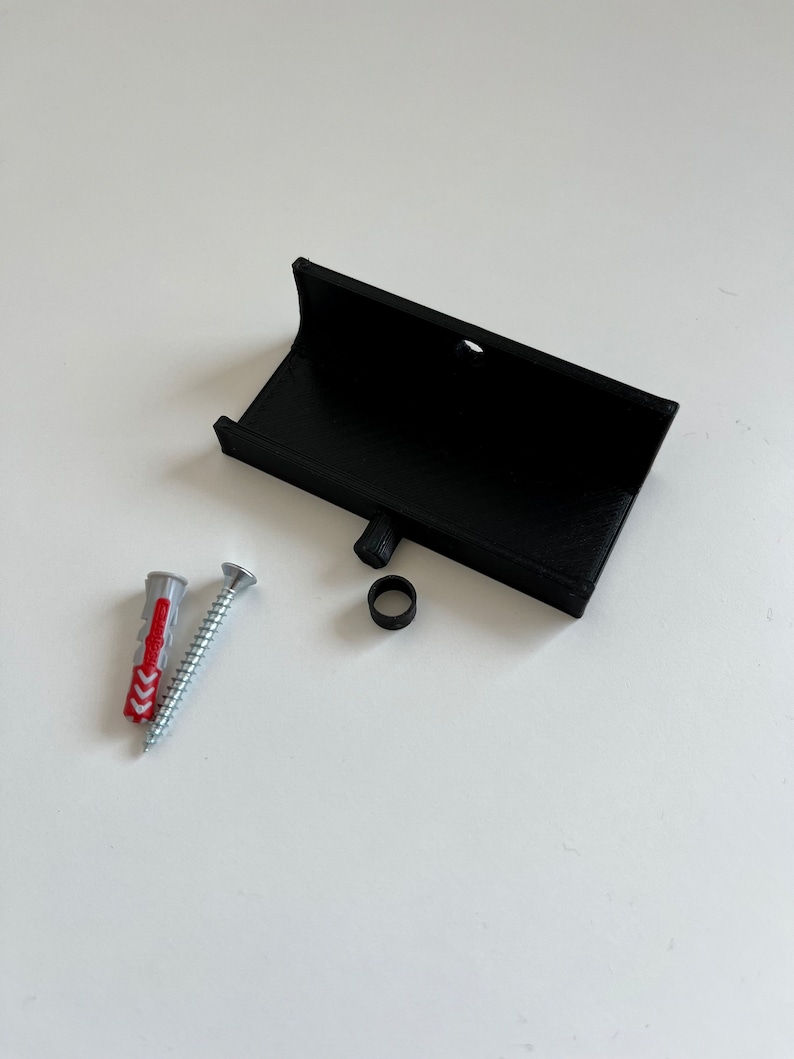 Peut inclure: Un support mural en plastique noir avec une vis, une cheville en plastique et un anneau en caoutchouc noir. Le support mural est con&ccedil;u pour tenir un petit objet, comme un t&eacute;l&eacute;phone ou une tablette.