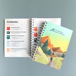 以下が含まれることがあります： 「The Ultimate Runner's Planner」というタイトルのスパイラル綴じプランナー。表紙には、ランナーのイラストが描かれています。開いたプランナーには、「Getting Started」などの番号付きセクションがある「Contents」ページが表示されています。